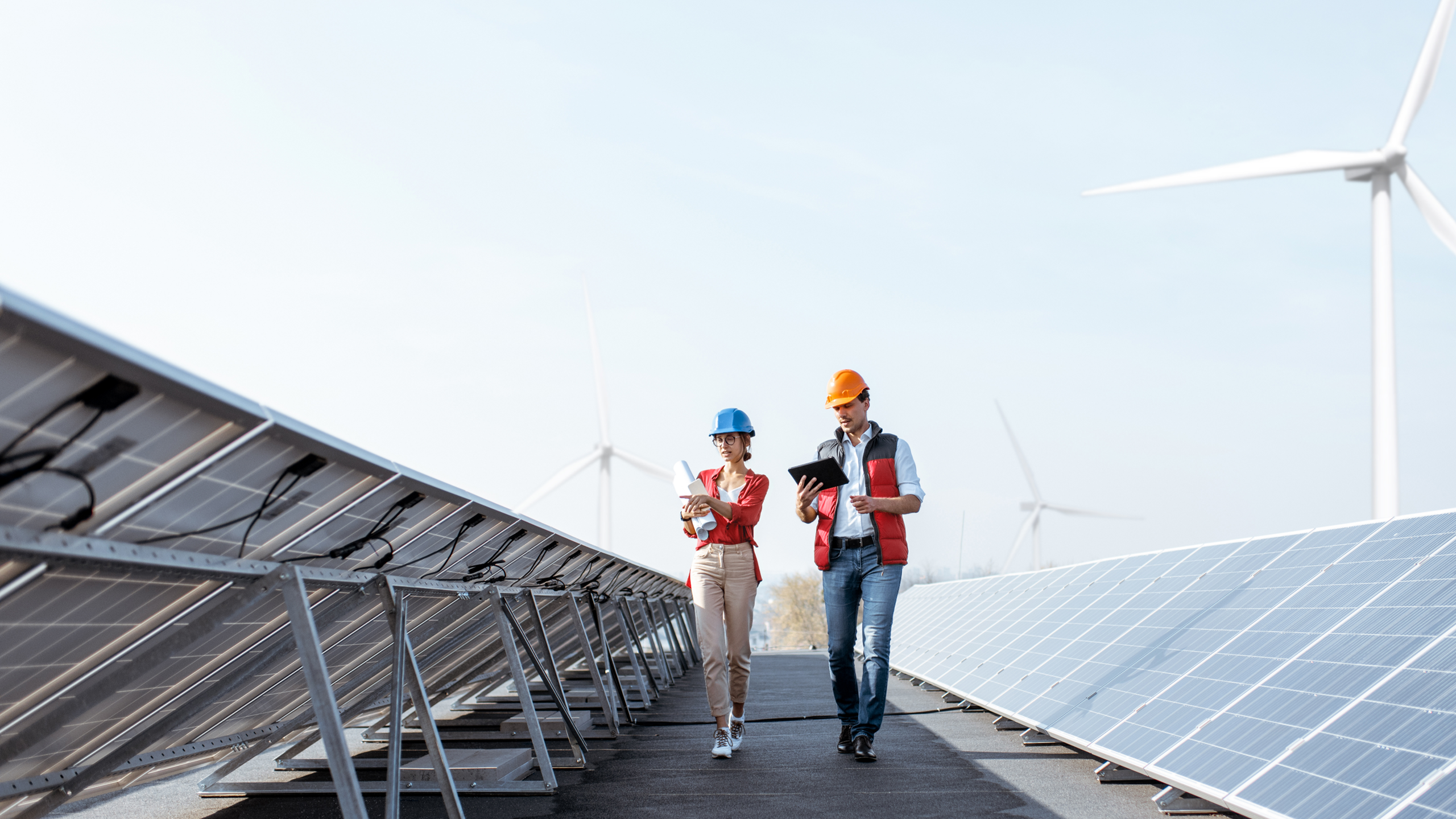 two workers walk along solar panels