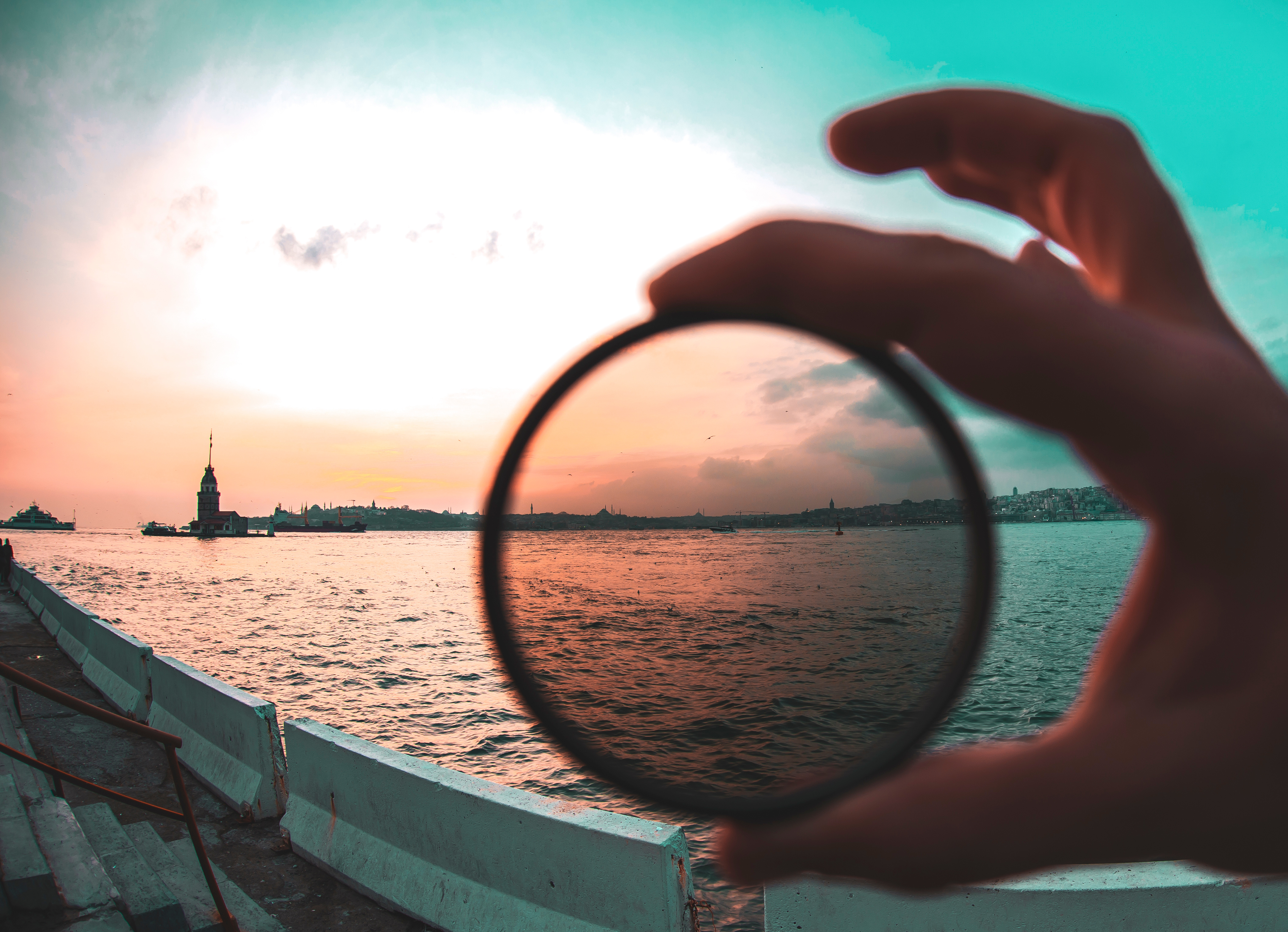 A view of a coast through a lens in a hand